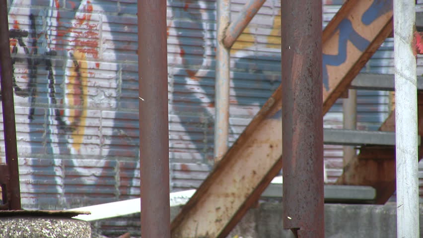 Video of old abandoned building covered with graffiti. Commercial equipment stairs painted by vandals. Destruction of private property. Zoom out. Wind blowing. Don Despain of Rekindle Photo