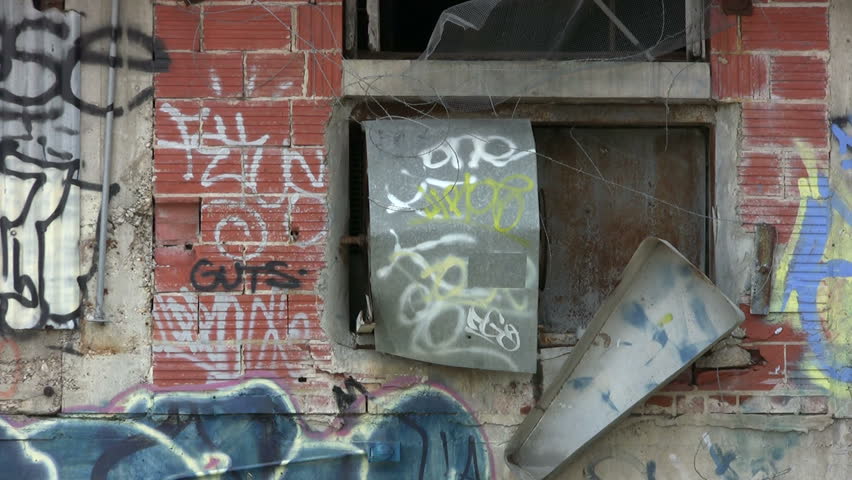 Video of old abandoned building covered with graffiti. Commercial equipment painted by vandals. Destruction private property. Zoom out window closeup. Wind blown weed. Don Despain of Rekindle Photo