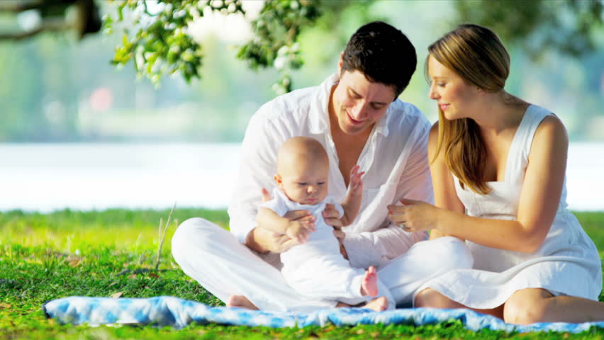Devoted young Caucasian parents playing with baby during picnic in park shot on RED EPIC