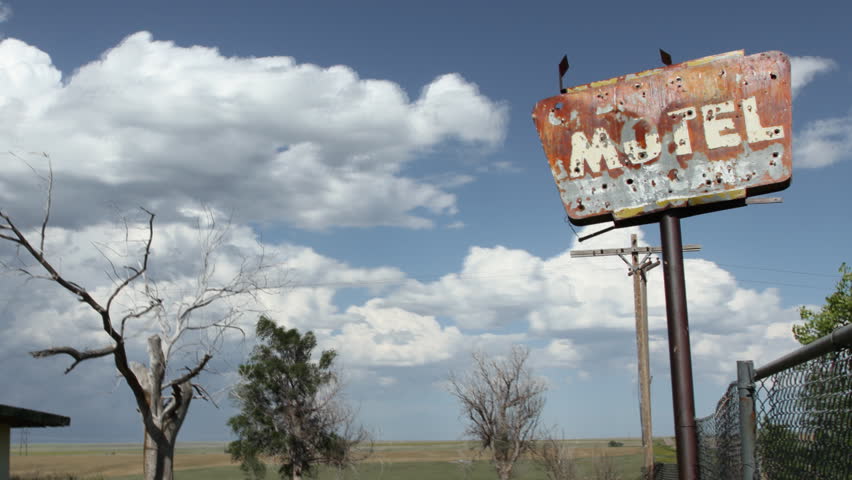 Timelapse of clouds behind an old, creepy motel sign, complete with bullet-holes, and old tree. HD 1080p Time lapse.