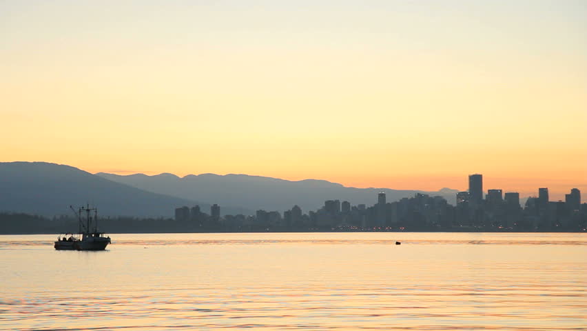 English Bay Dawn, Crab Boat, Vancouver. A commercial crab boat sets traps in English Bay at dawn with the Vancouver Skyline in the background. British Columbia, Canada.