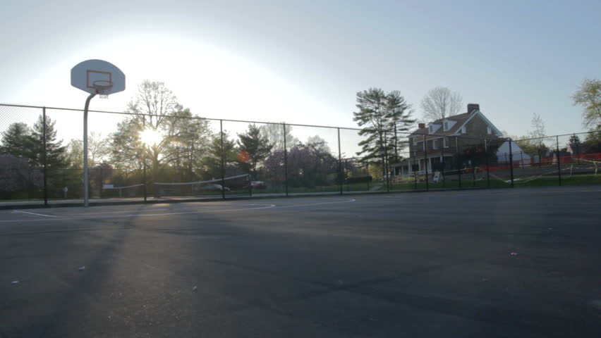Dolly of an outdoor basketball court as the sun sets.