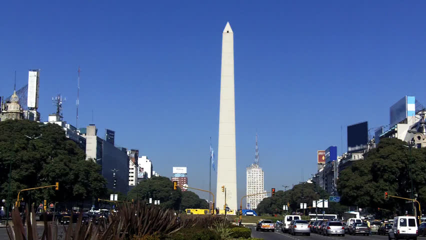Traffic in Buenos Aires - Traffic in downtown Buenos Aires with a view of El Obelisco. The Argentine flag flutters in the foreground