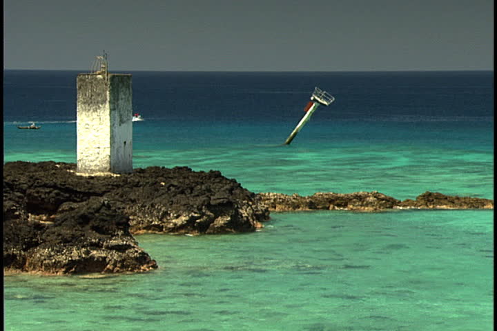 MORONI, UNION OF THE COMOROS (COMOROS ISLANDS), AFRICA - CIRCA NOVEMBER 1998: Rocky sandbar jutting out into turquoise waters. A speedboat passes in distance.