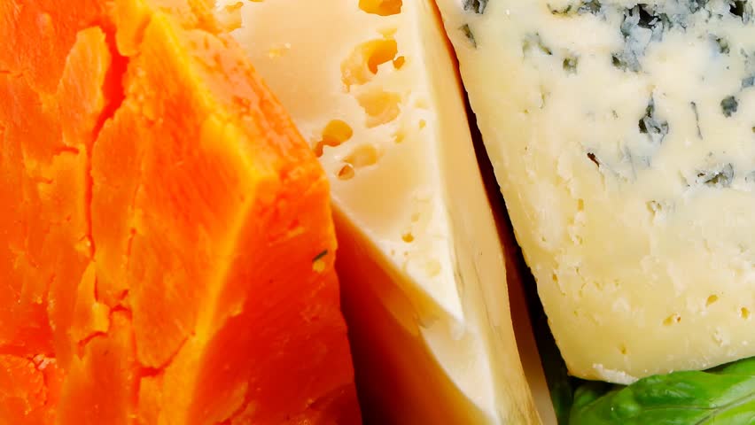 soft feta cheese with aged delicatessen cheeses on cutting wooden plate with tomatoes bread and olive oil