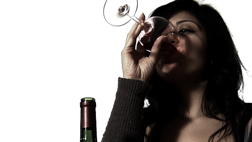 Woman drowning her sorrows - a young woman drinks a whole bottle of red wine alone - desaturated