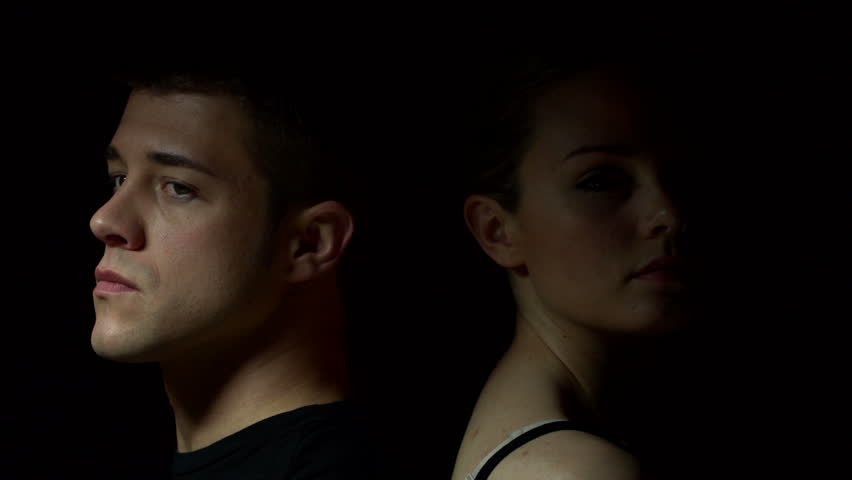 Man and woman sitting back to back in color. Experimental lighting.