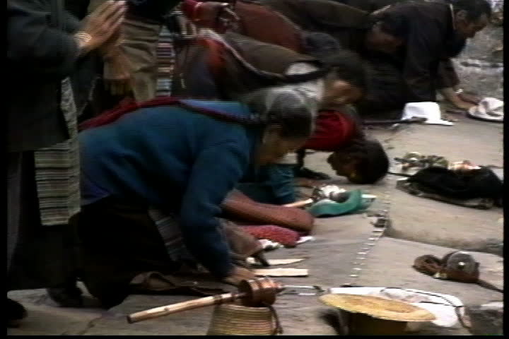 LHASA, TIBET - OCTOBER 1, 1993: Crowd of villagers bowing and praying before the juniper hearth on Barkhor Street.