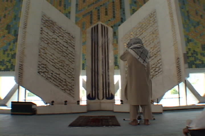 ISLAMABAD, PAKISTAN - NOVEMBER 01, 2001: Man stands in front of giant replica of Koran inside Faisal Mosque.
