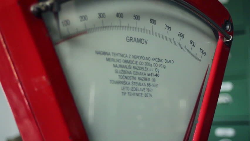 Close up shot of an old, retro, red scale and a seller that is weighting things