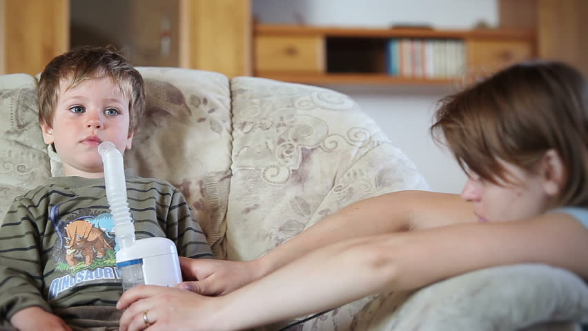 Mother and little boy using nebulizer to inhale medicine, front view