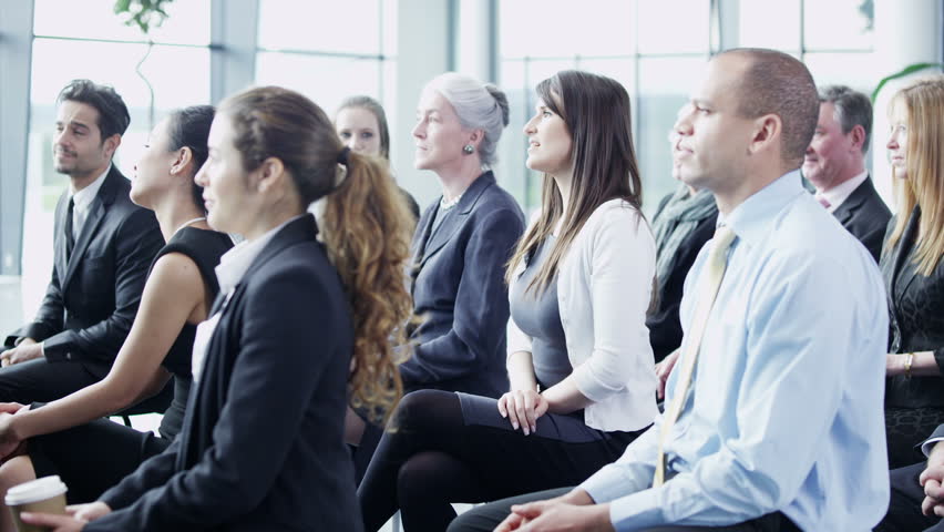 A multi ethnic group of business people of mixed ages are listening to a presentation at a business seminar and asking questions. In slow motion. 