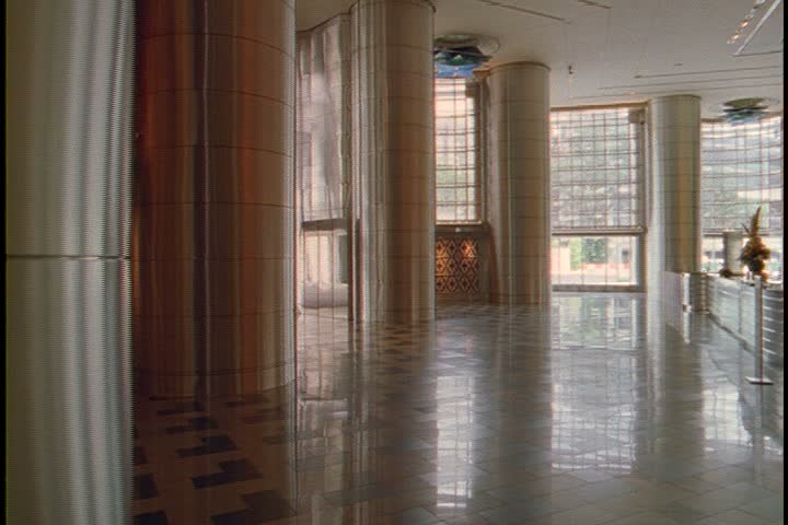KUALA LUMPUR - OCTOBER 22, 1999: Petronas Towers interior lobby; pan right past CU brass pillar to CU big glass entrance and doors. 