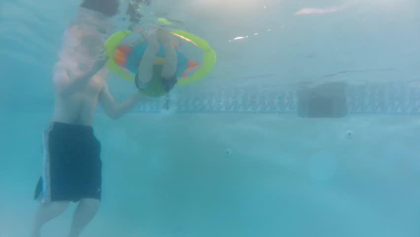 Underwater shot of a cute little baby boy at the swimming pool with his family.