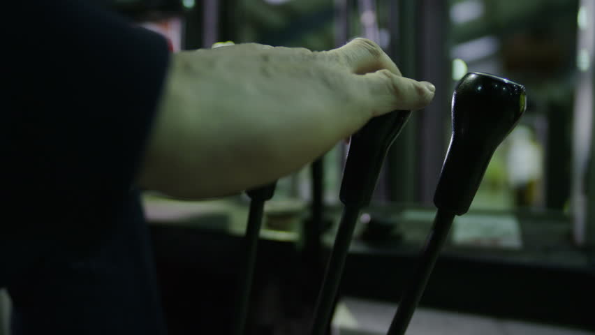 Close up view of the hand of an anonymous forklift truck driver. He is changing the gears as he drives and goes about his work in a factory or warehouse.