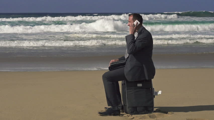 Young businessman talking on cellphone on the beach
