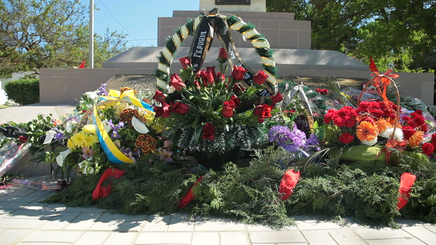 Remembrance wreaths and flowers on WW II war memorial. Tilt shot