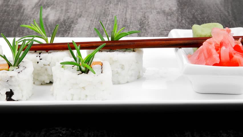Japanese Cuisine - California Roll made of Salmon Cream Cheese and Avocado inside. Served with wasabi and ginger . on long white plate over black table 1920x1080 intro motion slow hidef hd