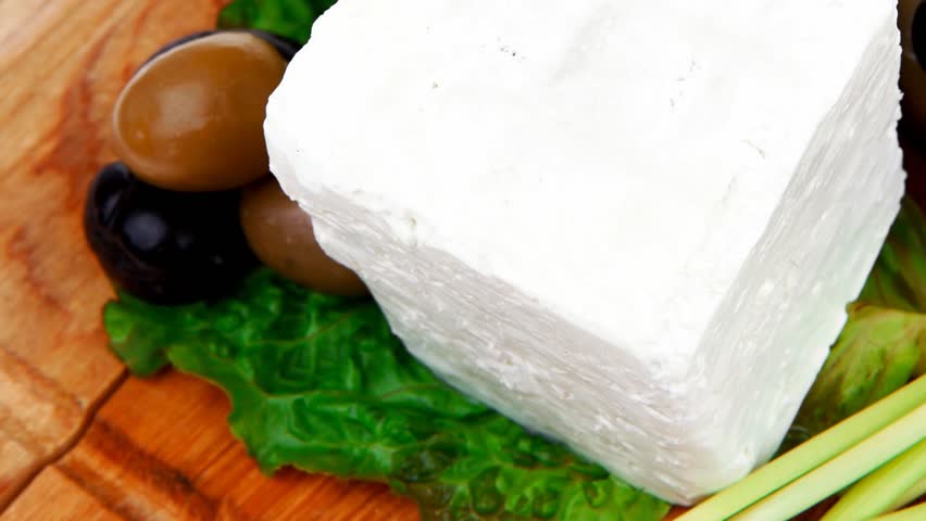 dairy food : feta white cheese cubes and round served on wooden cut plate with green leaves and olive oil 1920x1080 intro motion slow hidef hd
