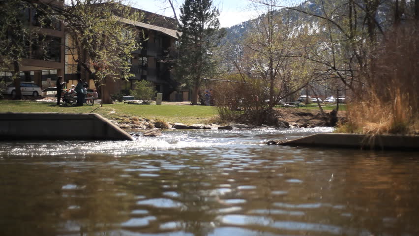 A mountain stream flowing past people enjoying the day outside of multifamily dwellings.