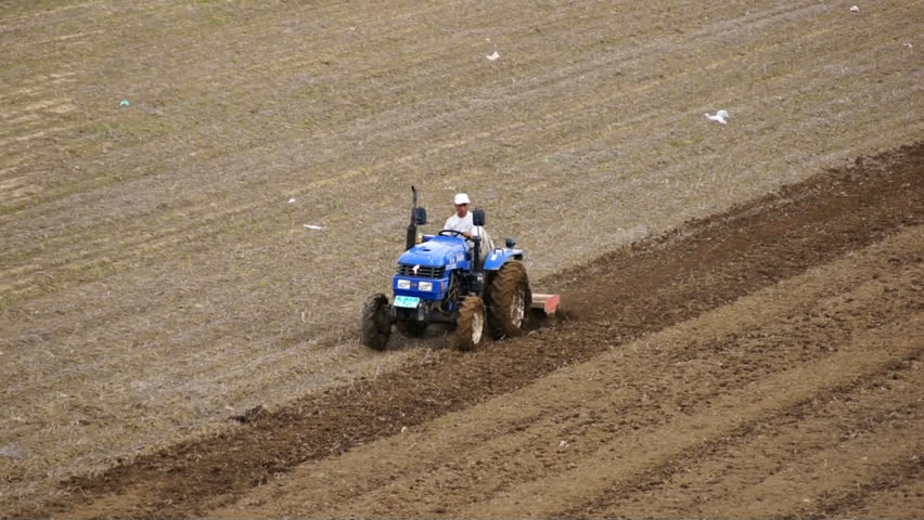 HEILONGJIANG PROVINCE, CHINA - CIRCA MAY 2013: Tractor plowing the field (06). Chinese farmer on a small tractor plowing a field in spring day. Tracking shot. North China, Heilongjiang Province, May 2013.