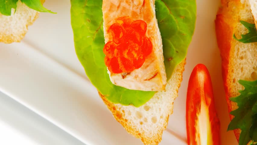 small salmon sandwiches served with caviar and olives