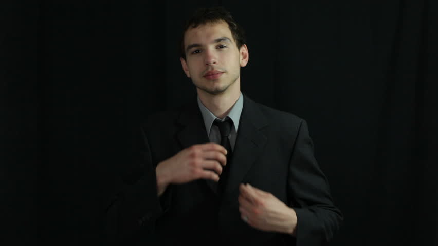 Uncomfortable businessman adjusting his necktie, over dark background