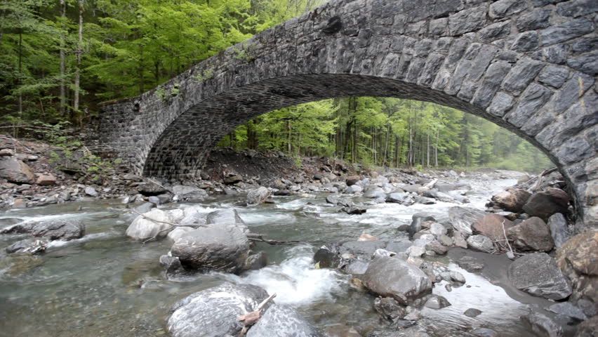 Montain river with an ancient stone bridge in Swiss Alps