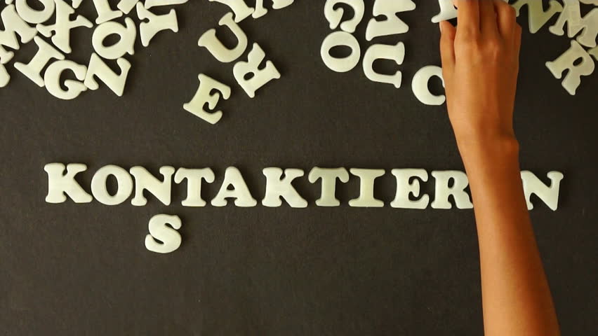 A person spelling Contact Us with Plastic letters (In German)