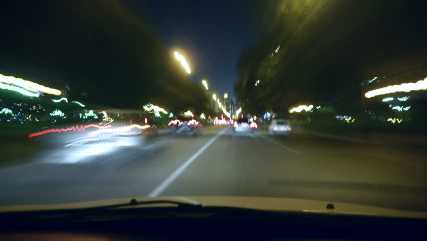 Driving a car time-lapse. POV - point of view. Night, Camera in the front, windshield reference. City, blurred motion, fast driving. HD.