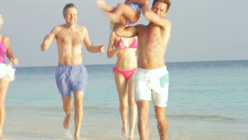 Multi Generation Family Having Fun In Sea On Beach Holiday
