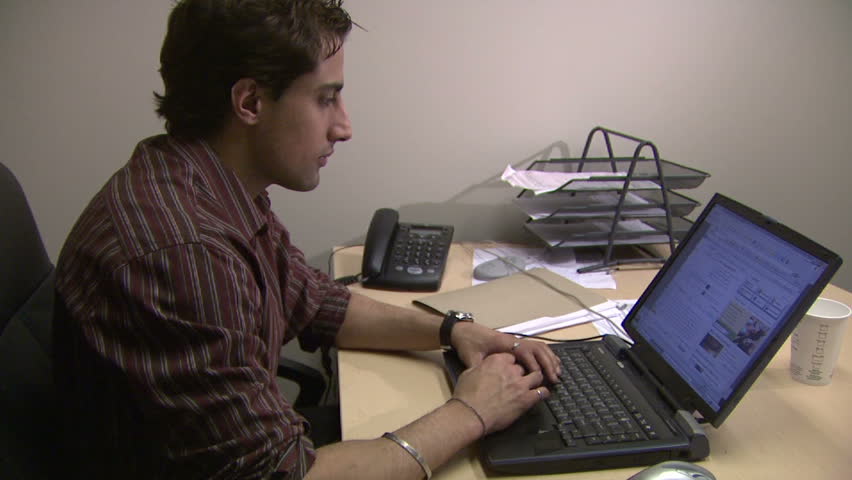 Employee researching Internet in his office. Perfect shot as a B-roll for a story on business/ work related issues or on Internet addiction.