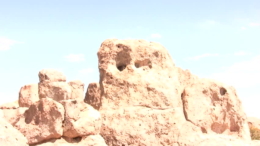 HD clip of a wide view of a rock formation, zooming into one of the holes, where a Great Horned Owl is sleeping quietly just out of the breeze