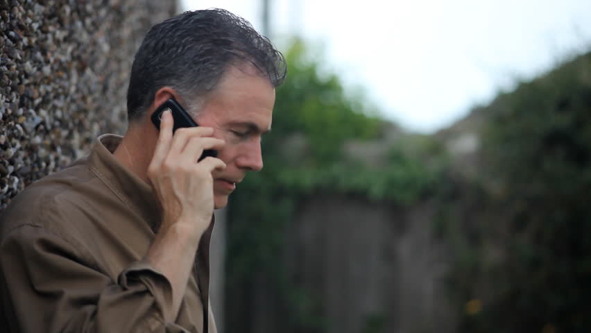 A man outside using wireless service to chat with someone via his cell phone.