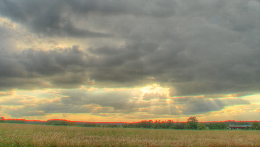 Clouds passing over fields with sun rays, HDR (high dynamic range) time lapse clip