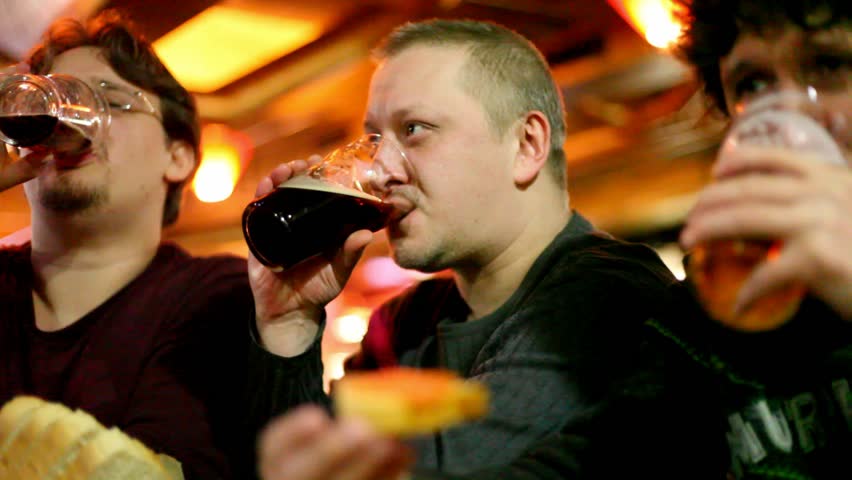 Three mans clink glasses and drink beer 