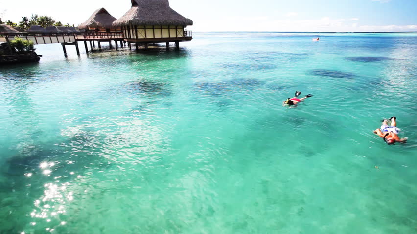 Young couple snorkeling in clean water next to resort