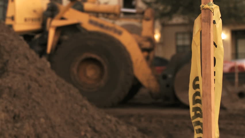 A ripped caution sign blowing in the wind at a construction site.