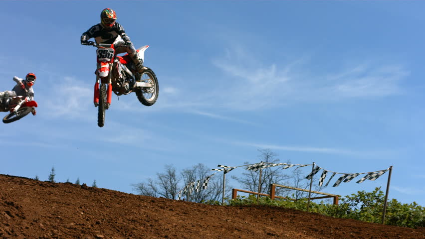 Motocross racers fly over jump, slow motion