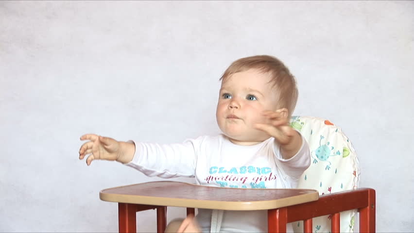 Baby sits at a children's little table. Mum feeds the child with porridge. Isolated on the white.