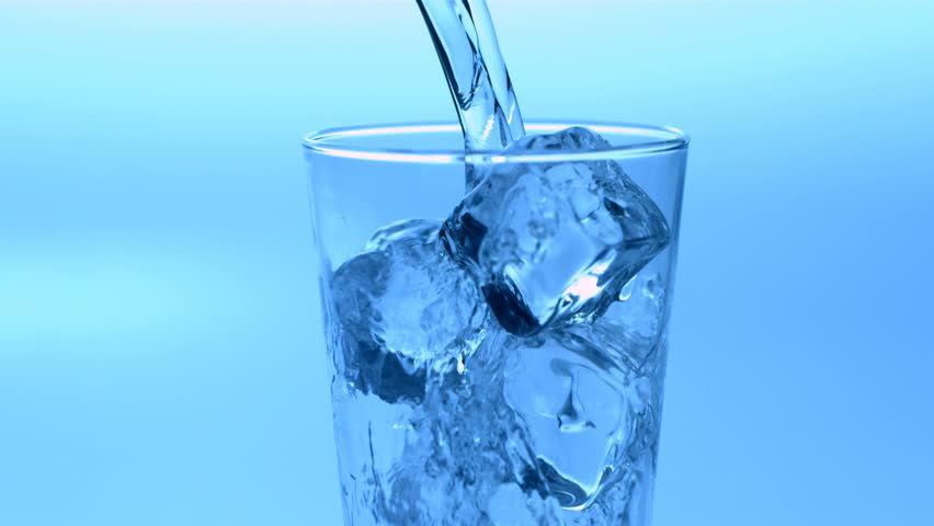 Pouring water over glass of ice cubes