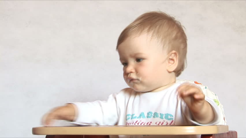 Baby sits at a baby's table. Mom gives to drink water of the child. Isolated on the white.