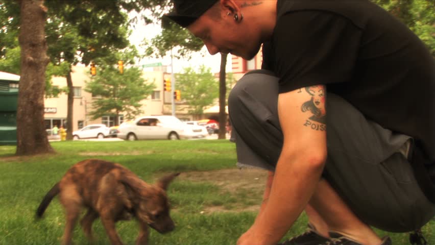 (1111) Young Couple Playing with Puppy in the Park. Good for themes of youth culture, alternative lifestyles, relationships, dating, romance, fashions  and emotions.