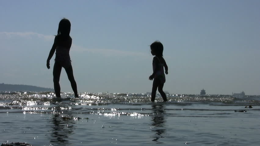 Little girls dancing in the surf on a glorious sunny summer afternoon.