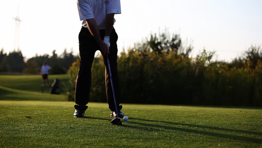 Close up of golf ball sitting on tee with driver swings and hits the ball