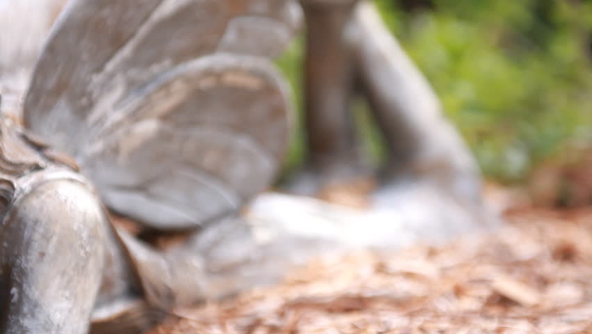 The camera dollies across a statuette of a little fairy lying down reading a book.