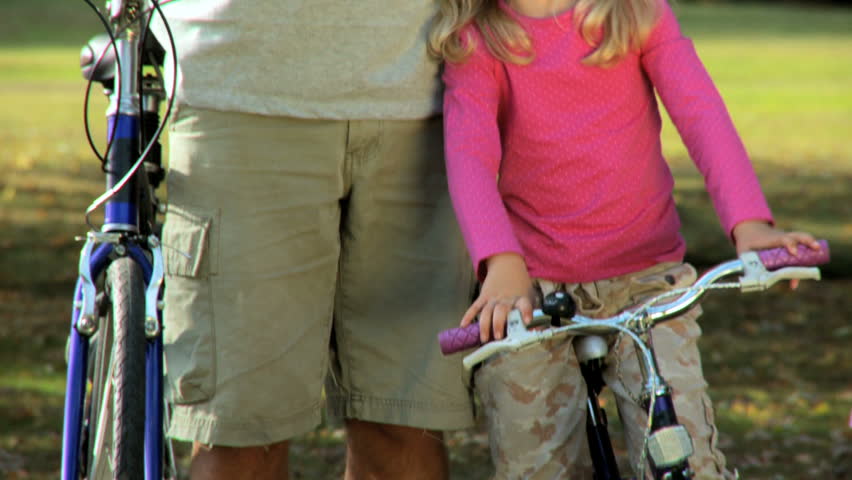 Father & daughter prepare to go cycling together on a summers day