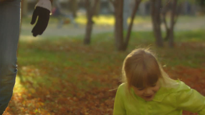 Sequence of slow motion shots of the happy mum and the little girl throw autumn leaves.
