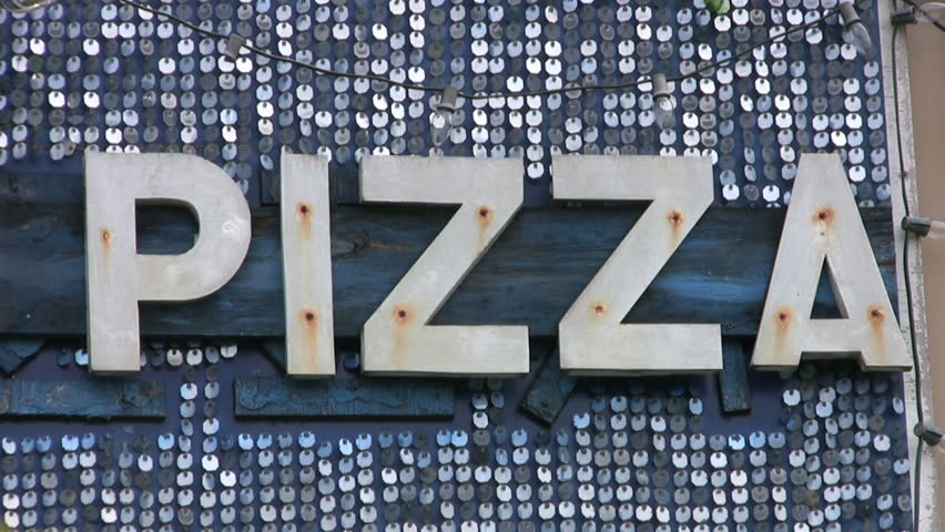 A cool, retro-style PIZZA sign glitters in the midday sun inviting customers to come and have some tasty PIZZA.