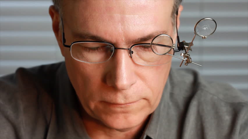 A man wearing jewelerÃÂ¢??s glasses adjusts the magnifiers, and begins to examine something off screen.